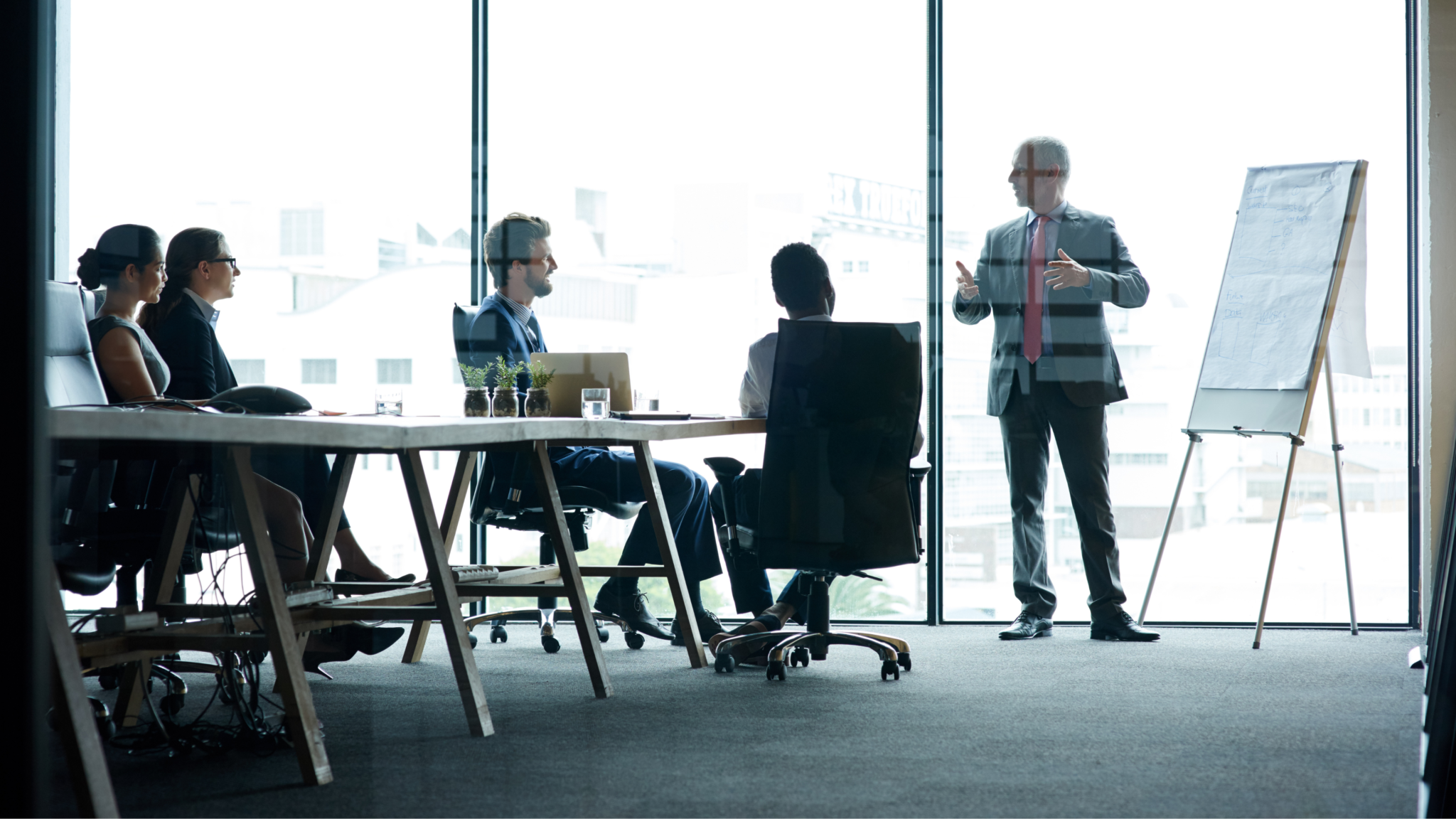Business professionals in a meeting room with a presenter at a whiteboard