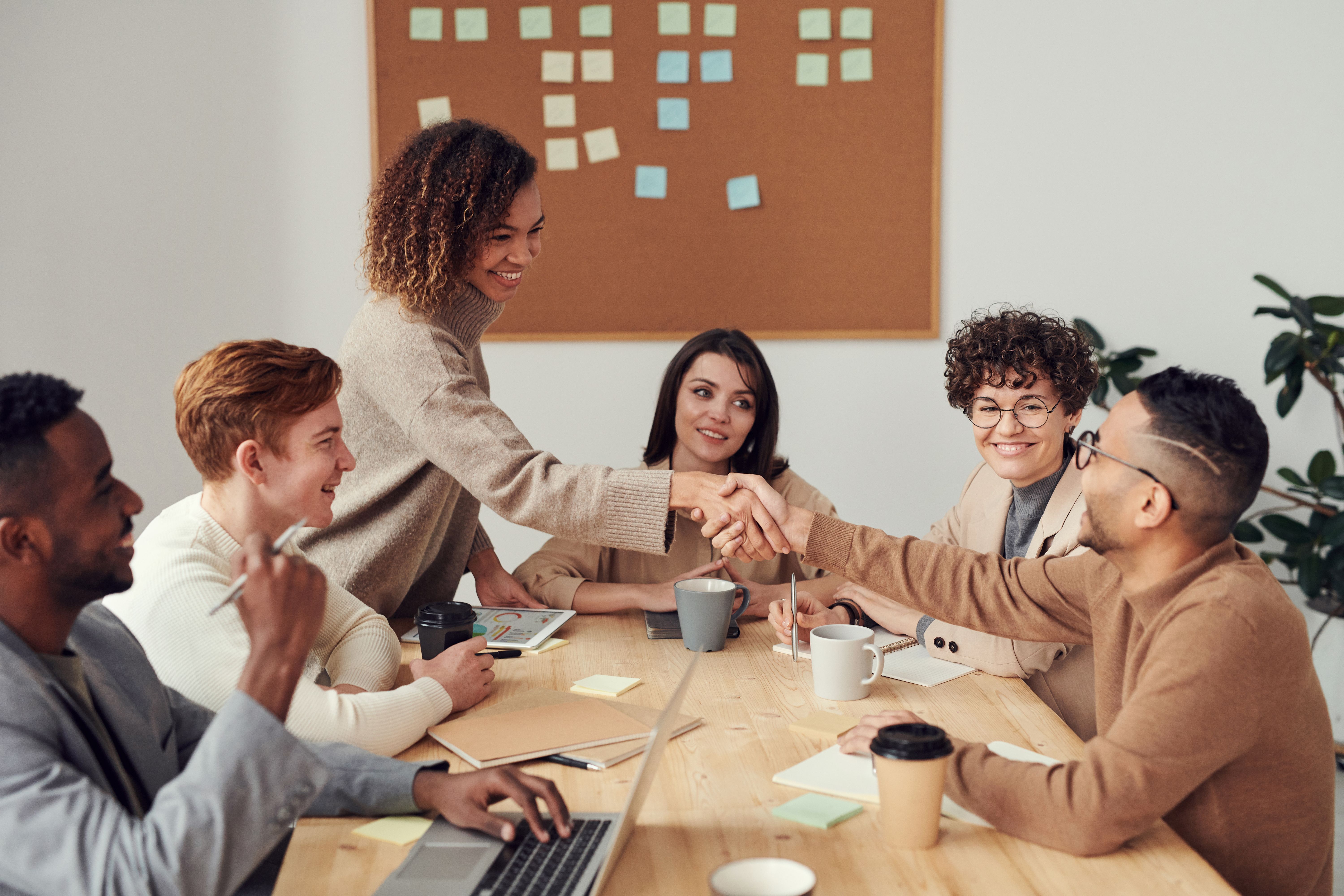Diverse team smiling and shaking hands in a meeting